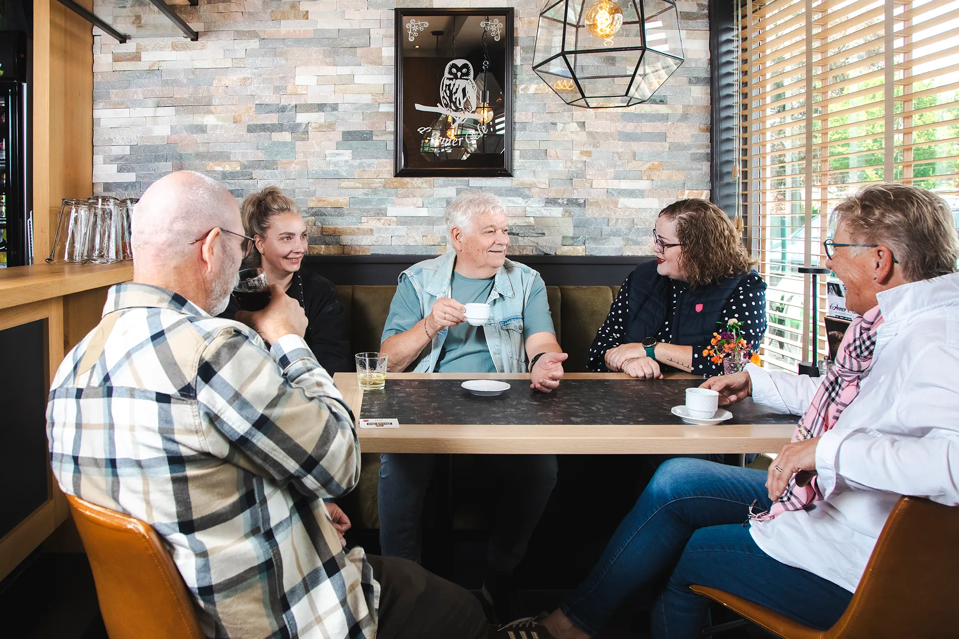 Een groep mensen zit samen gezellig te praten in een café.
